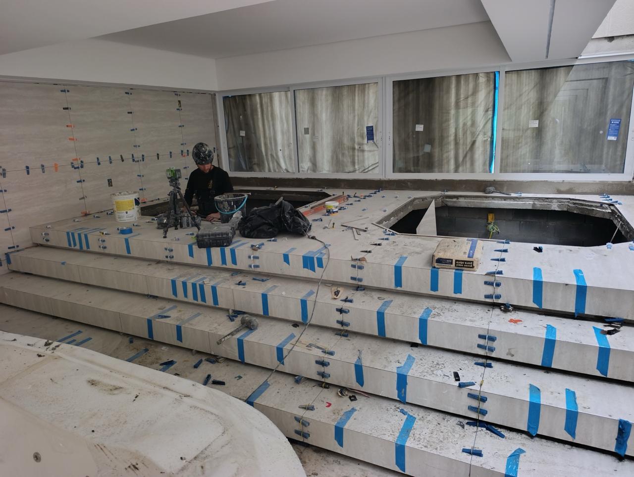 Profissional da Construtora Empório assentando porcelanato com nivelamento técnico em obra de alto padrão