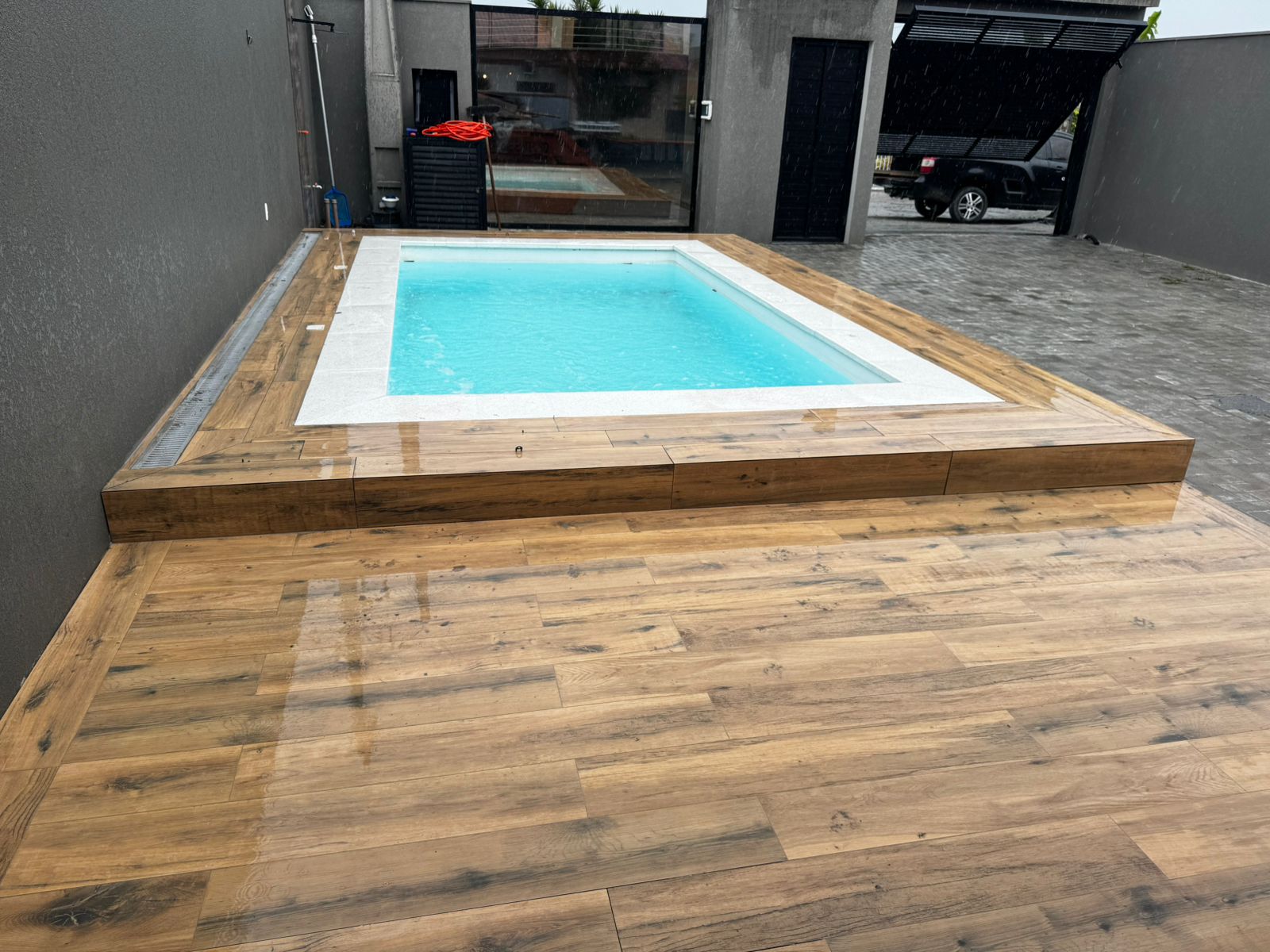 Área de lazer entregue com piscina e deck revestido em porcelanato amadeirado