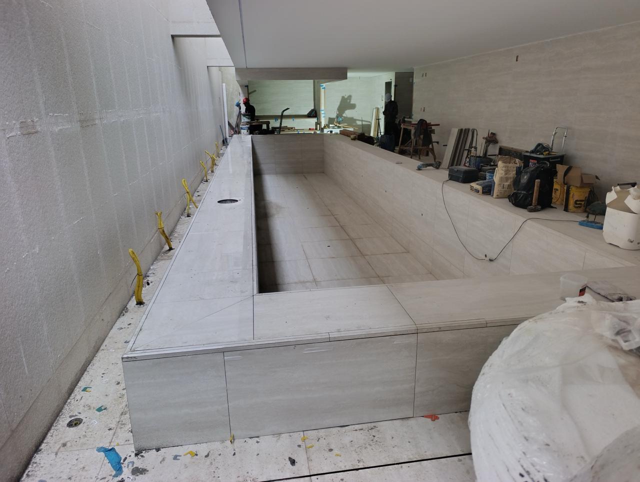 Revestimento em porcelanato de grande formato aplicado em área de piscina, acabamento de alto padrão