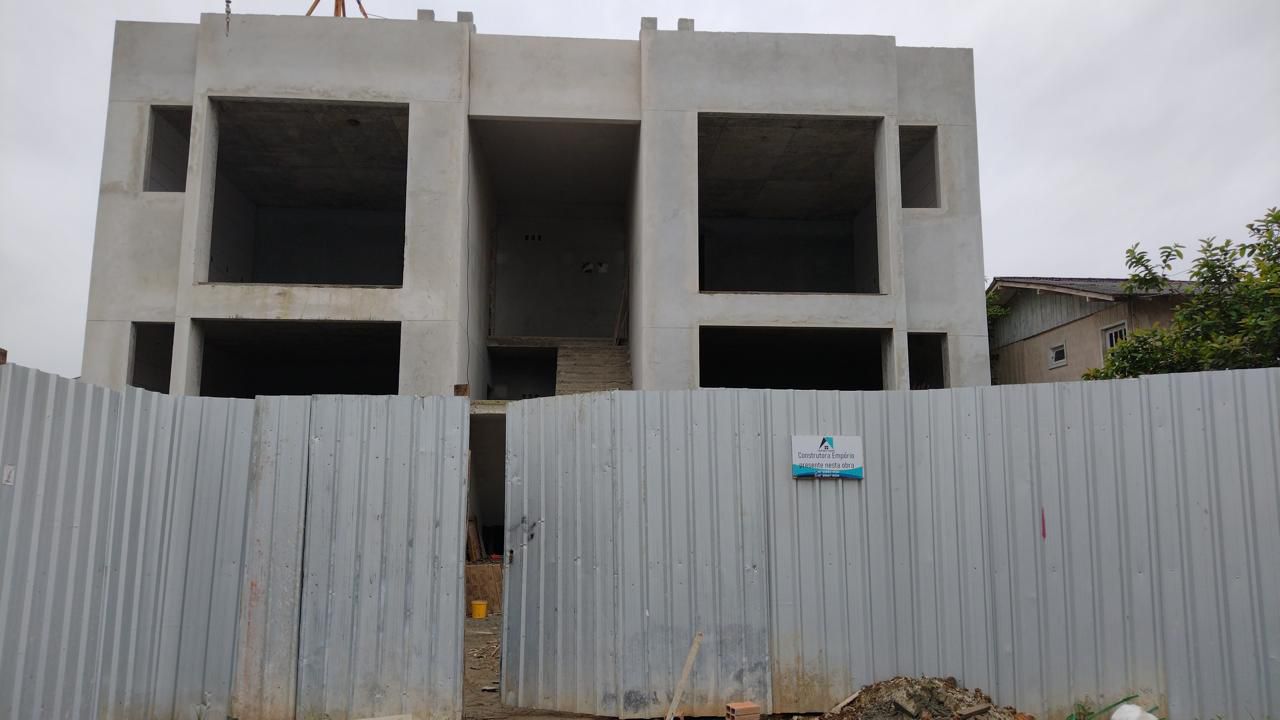 Sobrado geminado em construção com placa da Construtora Empório no tapume
